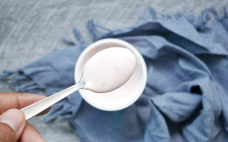 colher com iogurte sobre um pote de iogurte