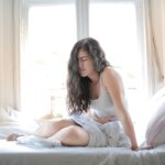 Mulher na cama com dor de estômago