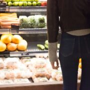 mujer de pie frente al supermercado de la tienda de comestibles de verduras y frutas