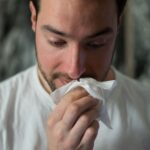 homem a limpar o nariz com lenço de papel