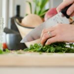 person cutting vegetables with knife herbs