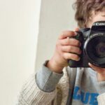 menino segurando câmera Canon DSLR