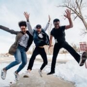 photo de trois hommes sautant au sol près d'arbres dénudés pendant la journée