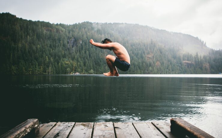 homem pulando em um lago durante o dia