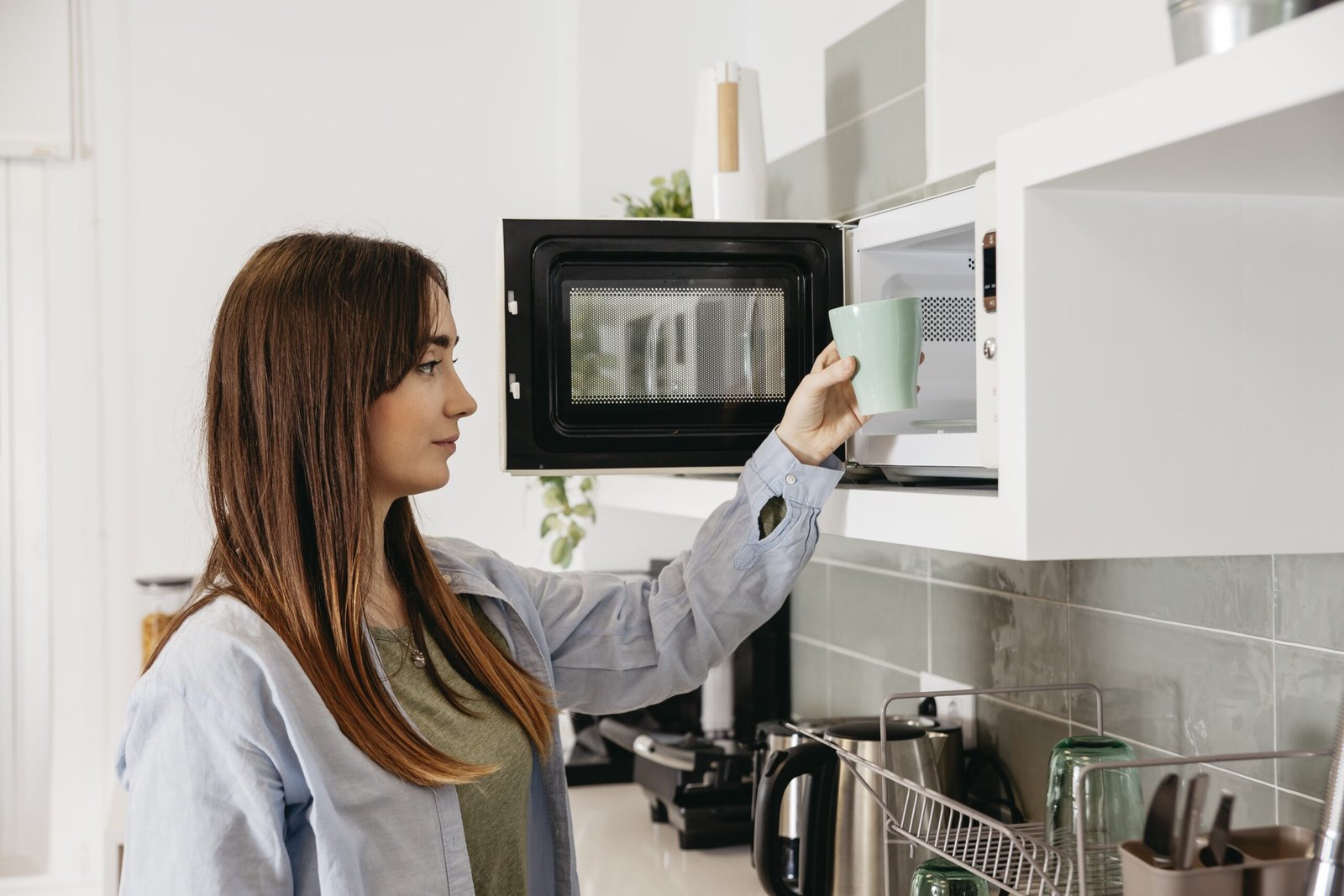 mujer metiendo un vaso al microondas para calentar el contenido