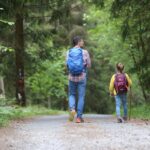 homem de jaqueta azul e jeans azul caminhando na estrada de terra durante o dia do pai e filho