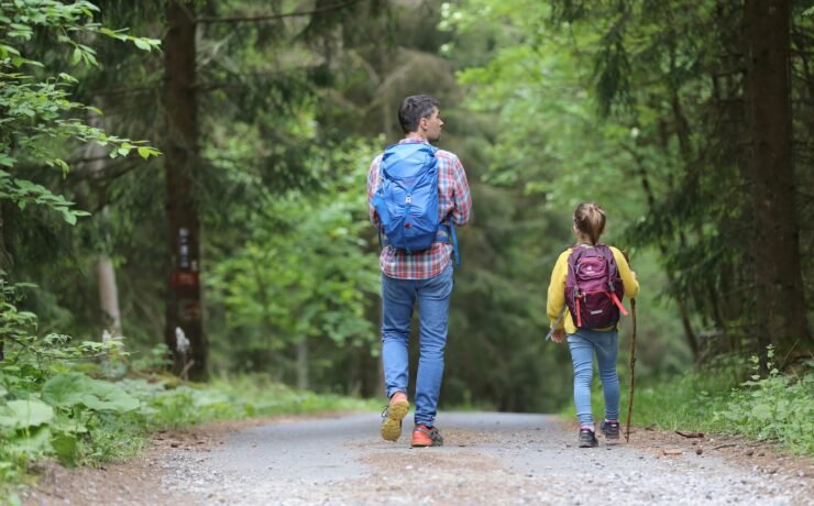 man in blue jacket and blue denim jeans walking on dirt road during daytime father son