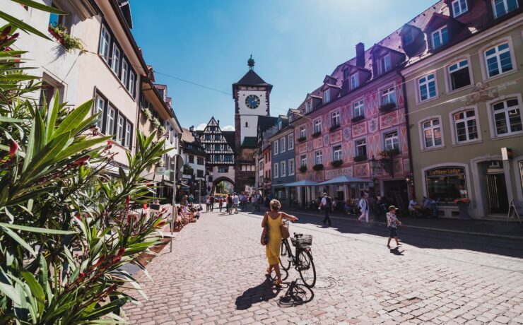 a woman riding a bike down a cobblestone street freiburg