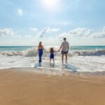 homem, mulher e criança de mãos dadas à beira-mar à beira-mar