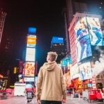 homem parado na rua em frente ao arranha-céu nova york