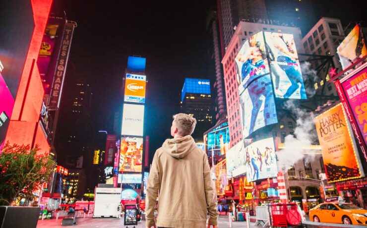 man standing on road infront of high-rise buildi new york