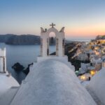 edifício de concreto branco perto do corpo de água durante o pôr do sol santorini grécia mar