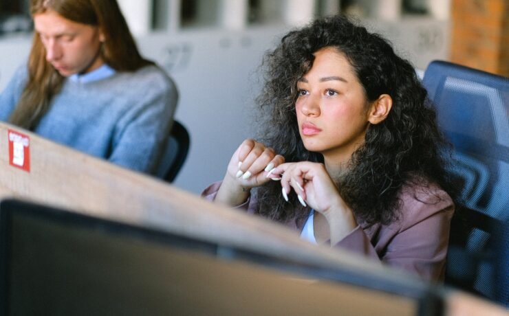 High angle of concentrated female employee sitting at table in open space and thoughtfully looking away doubt office job