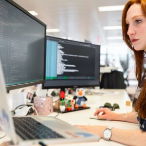 mulher de camisa verde sentada em frente a um escritório de computador trabalhando