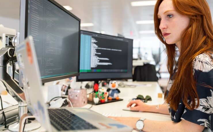 woman in green shirt sitting in front of computer office working