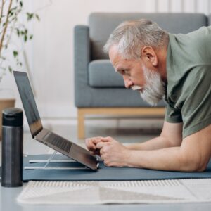 homem sênior trabalhando enquanto assiste curso de ioga para laptop