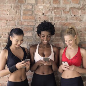 três mulheres amigas academia fitness smartphone sorriso alegria