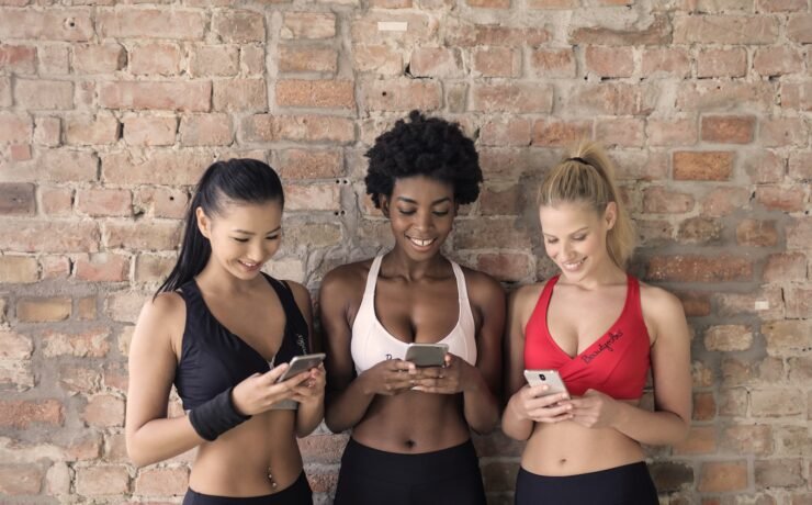 três mulheres amigas academia fitness smartphone sorriso alegria