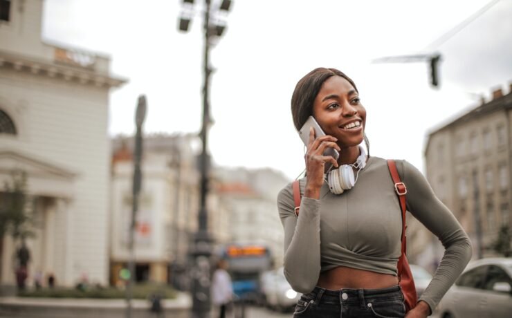 Smiling girl phoning while walking in the city