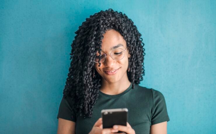 Girl in glasses texting with mobile phone in hand