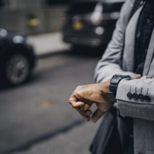 Homem na rua, na cidade, olhando as horas. Relógio, pontualidade