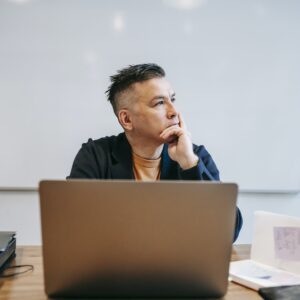 Foto de um homem pensando em frente a um computador
