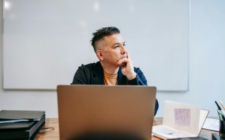 Foto de um homem pensando em frente a um computador