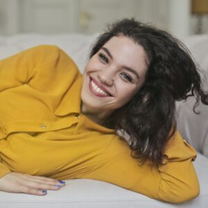 mulher de moletom amarelo no sofá sorrindo