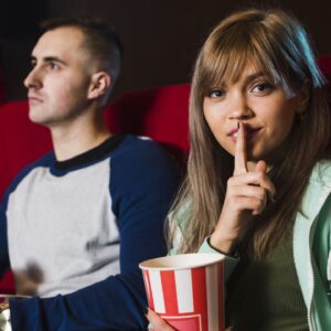 Garota pede silêncio no cinema com garoto ao lado