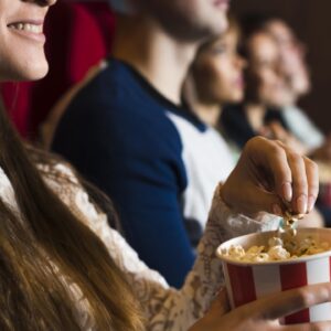 pessoas no cinema, garota sorrindo enquanto come pipoca