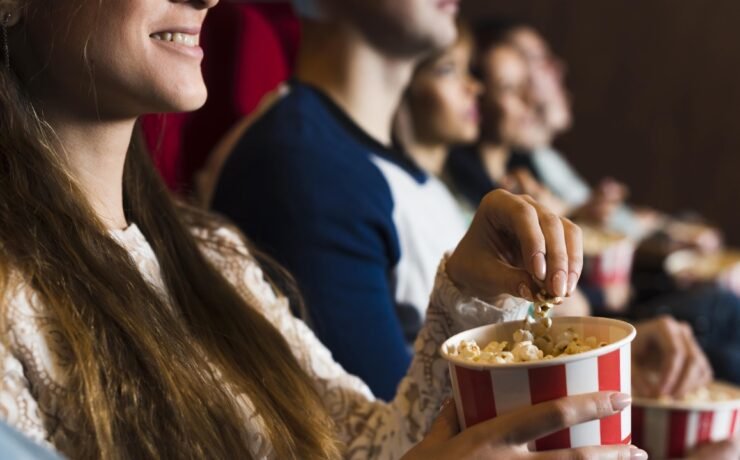 people in cinema, girl smiling while eating popcorn