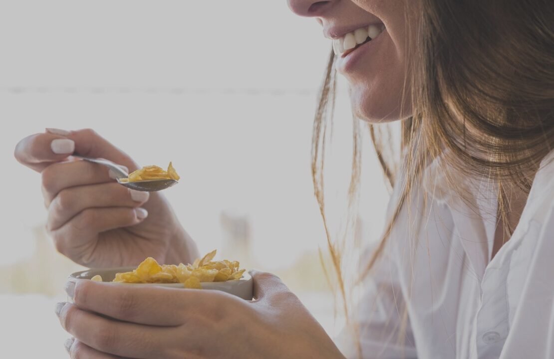 mulher comendo carvalhos café da manhã enquanto sorria