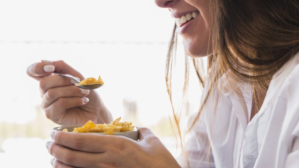 mulher comendo tigela de aveia no café da manhã enquanto sorri