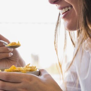 mulher comendo tigela de aveia no café da manhã enquanto sorri