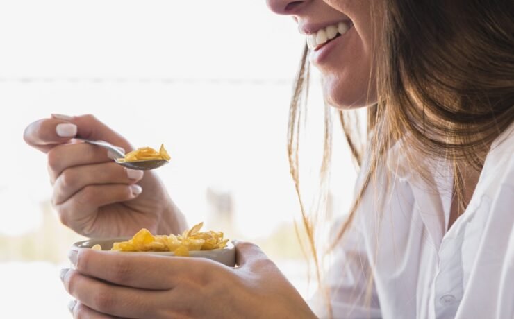 mulher comendo tigela de aveia no café da manhã enquanto sorri