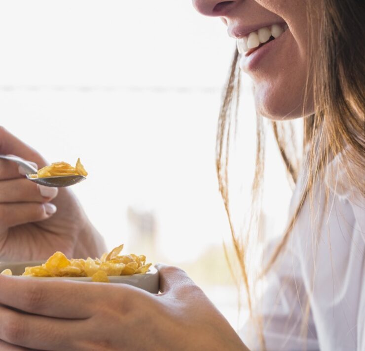 donna che mangia ciotola d'avena per colazione mentre sorride