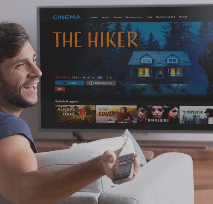 man looking at the television sit on a couch with popcorns