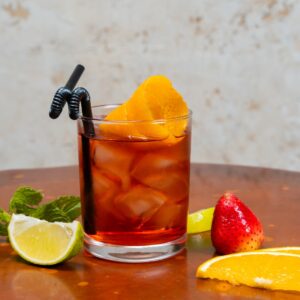 copo com refrigerante em cima de mesa, fatias de laranja e limão