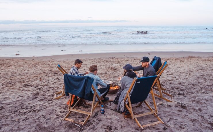 four friends on the beach talking and standing together