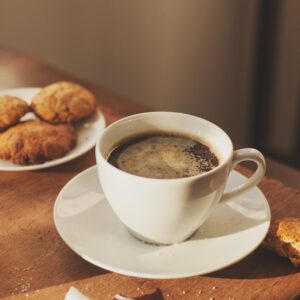 uma xícara de café, biscoitos, copinho d'água