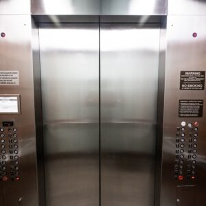interior de um elevador em aço escovado com visão da porta e dos botões
