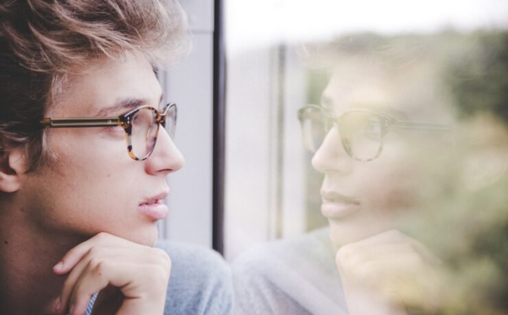 boy looking out the window, mirroring himself