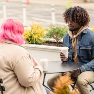 Menino ouvindo um amigo sentado em uma mesa em um café