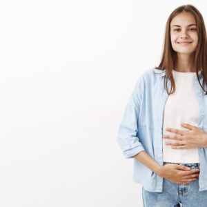Mulher sorrindo com o estômago se sentindo bem após a digestão