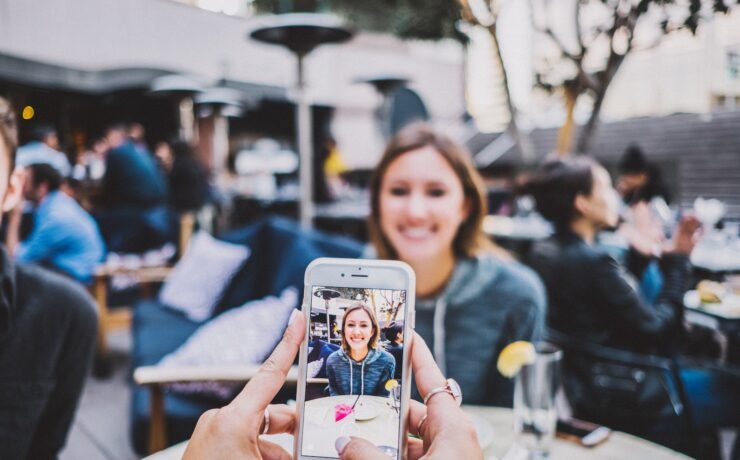 person taking a photo of a woman with a mobile phone