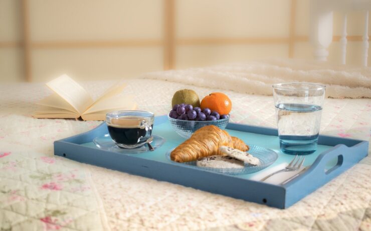 vassoio blu su un tavolo con croissant, caffè, bicchiere d'acqua