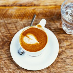 xicara de café com copo d'água sobre uma mesa de madeira