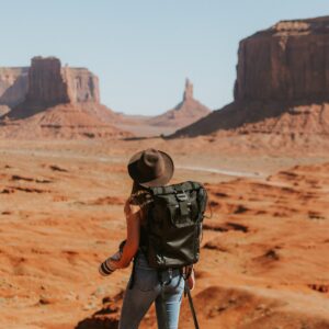 mulher com mochila preta em pé no deserto