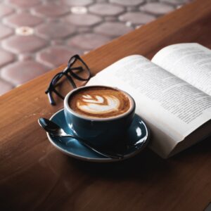 xícara de café sobre mesa, livro aberto