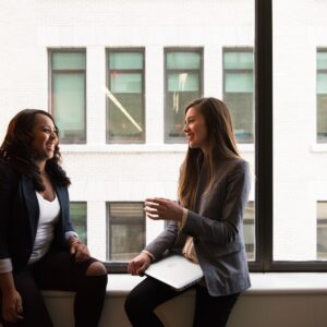 Duas mulheres sentadas à janela conversando